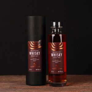 Holzfassgereifte Whiskyflasche der Edition 008, gefüllt mit bernsteinfarbenem Whisky, der Ex‑Bourbon- und sächsischen Regent‑Rotweineinfluss vereint.